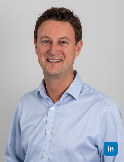 A profile image of a smiling, brown haired white man wearing a white buttoned shirt.