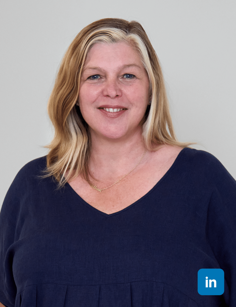 A profile image of a white woman with shoulder length golden blonde hair, two streaks of bright blonde frame her face. She wears a navy blue v-neck top.